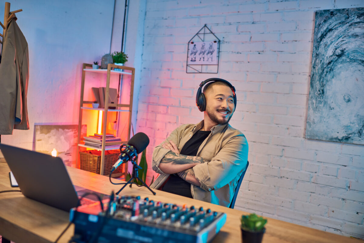 Un homme sourit dans un studio de podcast.